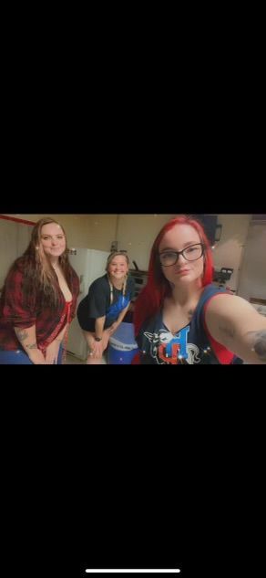 Three women are standing next to each other in a room taking a selfie.