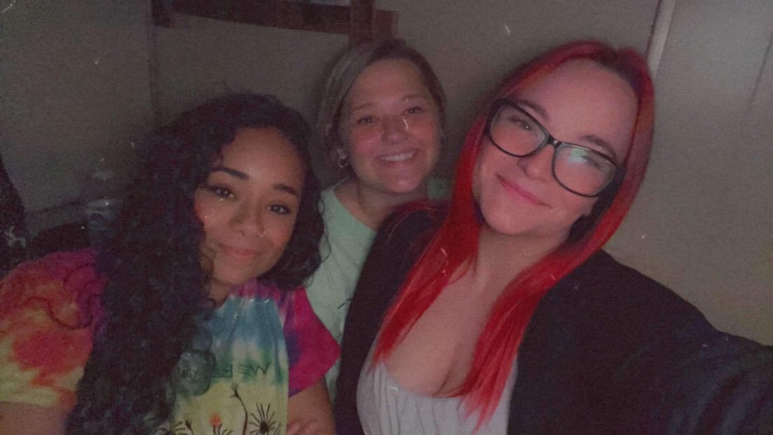 Three women are posing for a picture together in a dark room.