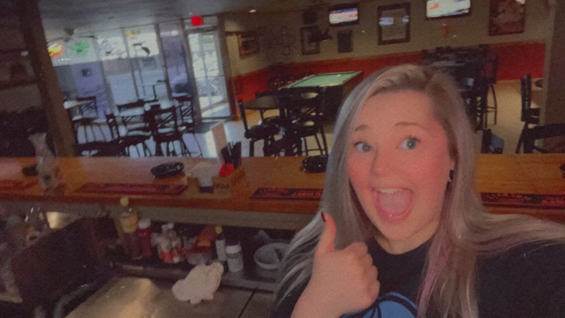 A woman is giving a thumbs up in a restaurant.