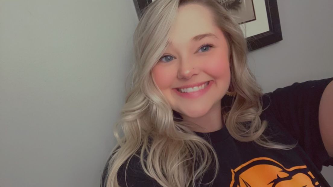 A woman in a black shirt is smiling and taking a selfie.