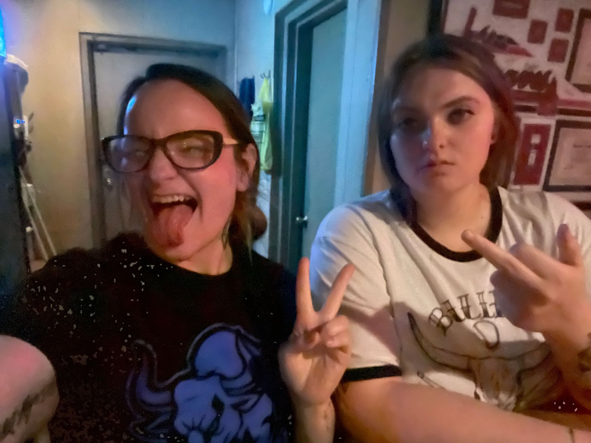 Two girls are posing for a picture and one is sticking her tongue out