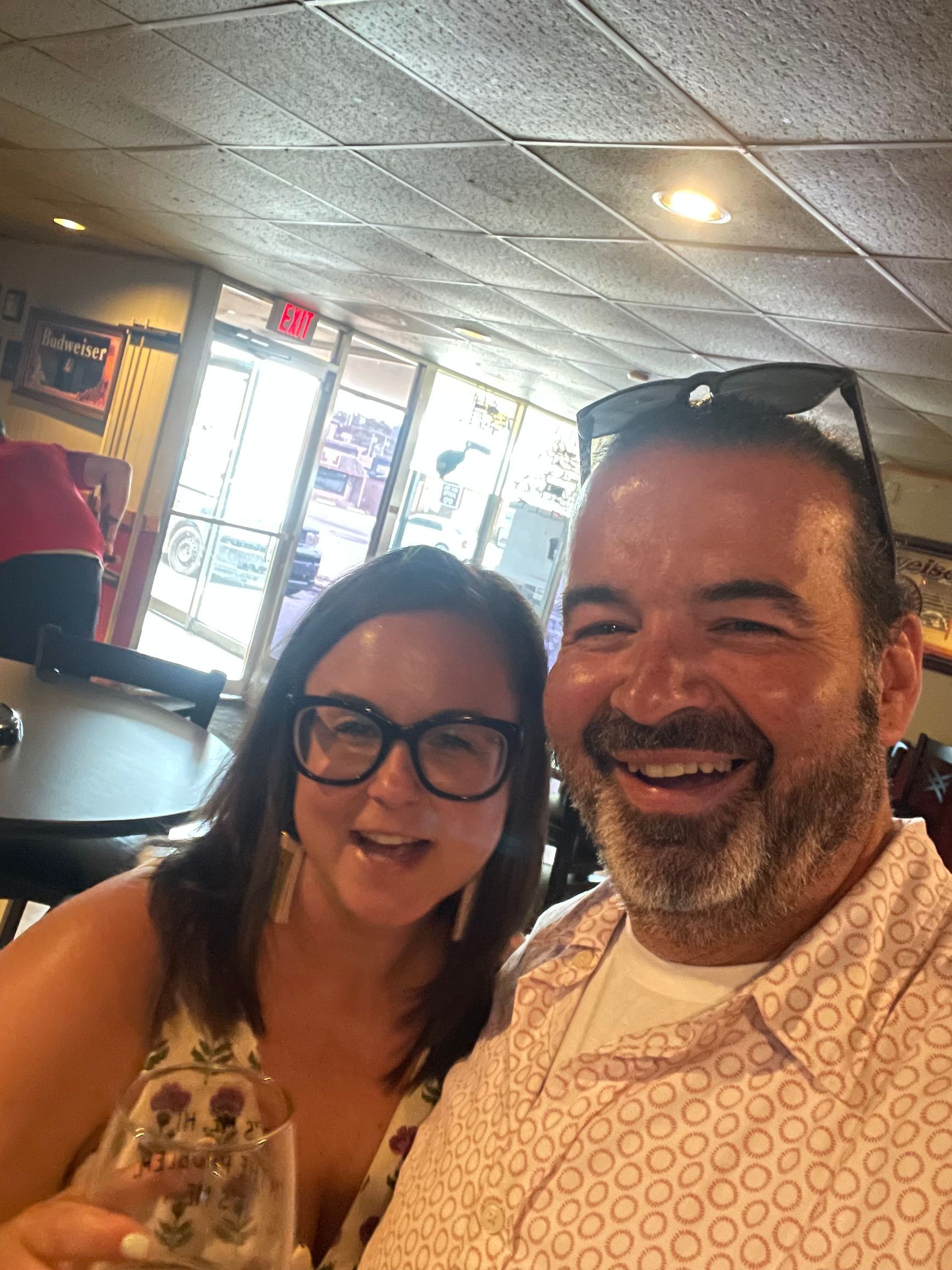 A man and a woman are posing for a picture in a restaurant.