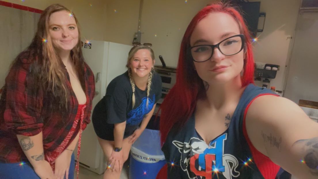 Three women are standing next to each other in a room taking a selfie.