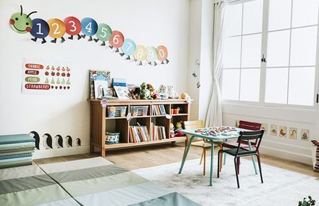 A child 's room with a table and chairs and a caterpillar on the wall.