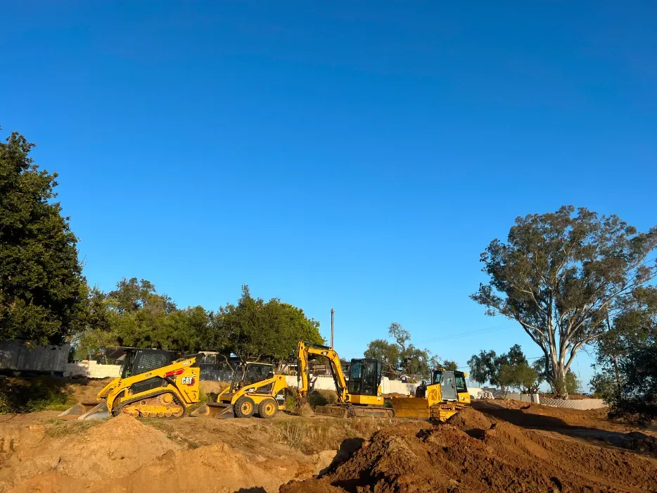 Construction site with yellow heavy machinery under a clear blue sky.