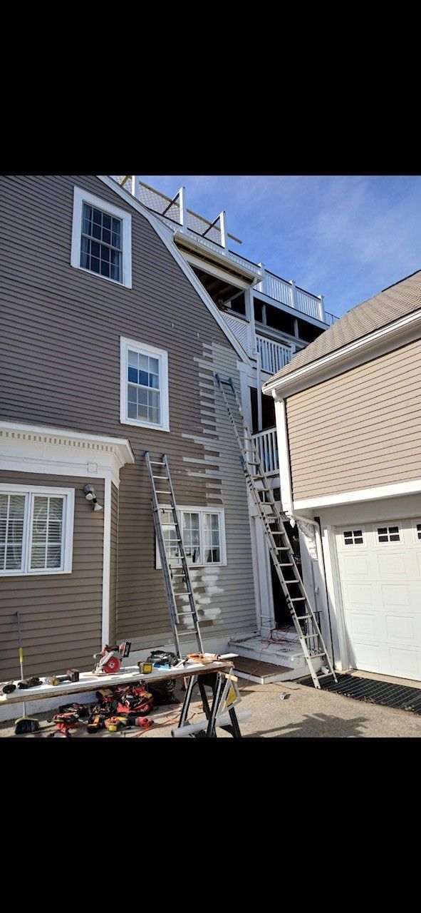 A house with a staircase leading up to the roof is being painted.