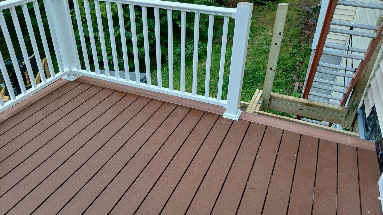 A wooden deck with a white railing is being built.