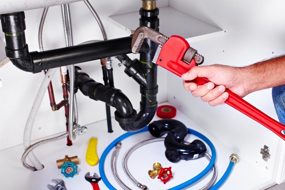 Plumber Hands With Wrench & Plumber Tools — Plumber in Albion Park, NSW