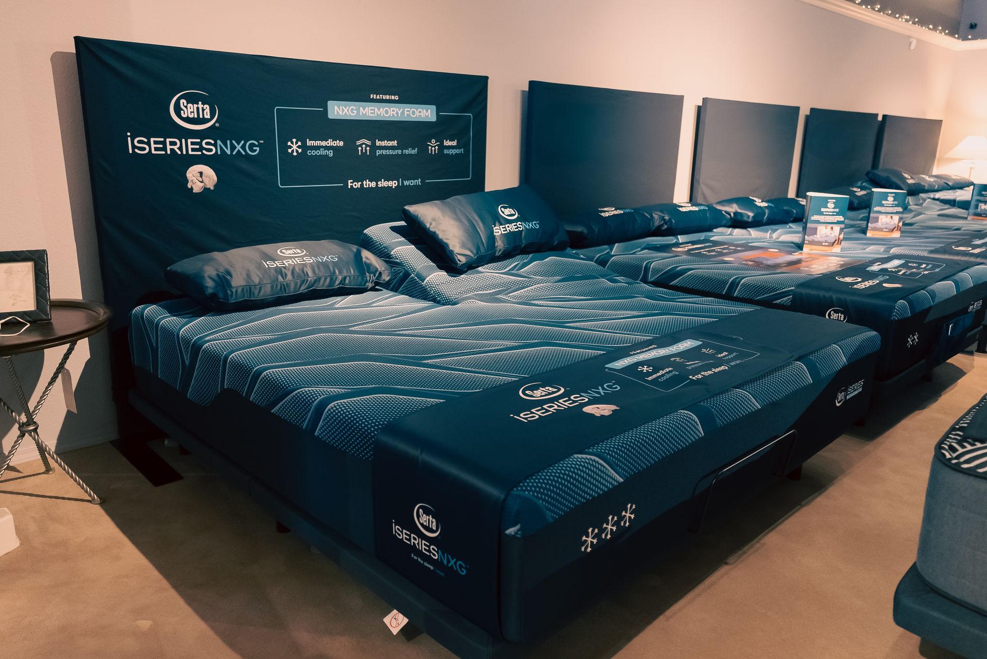 Rows of dark blue beds with white patterns in a showroom, displayed against a wall with matching headboards.