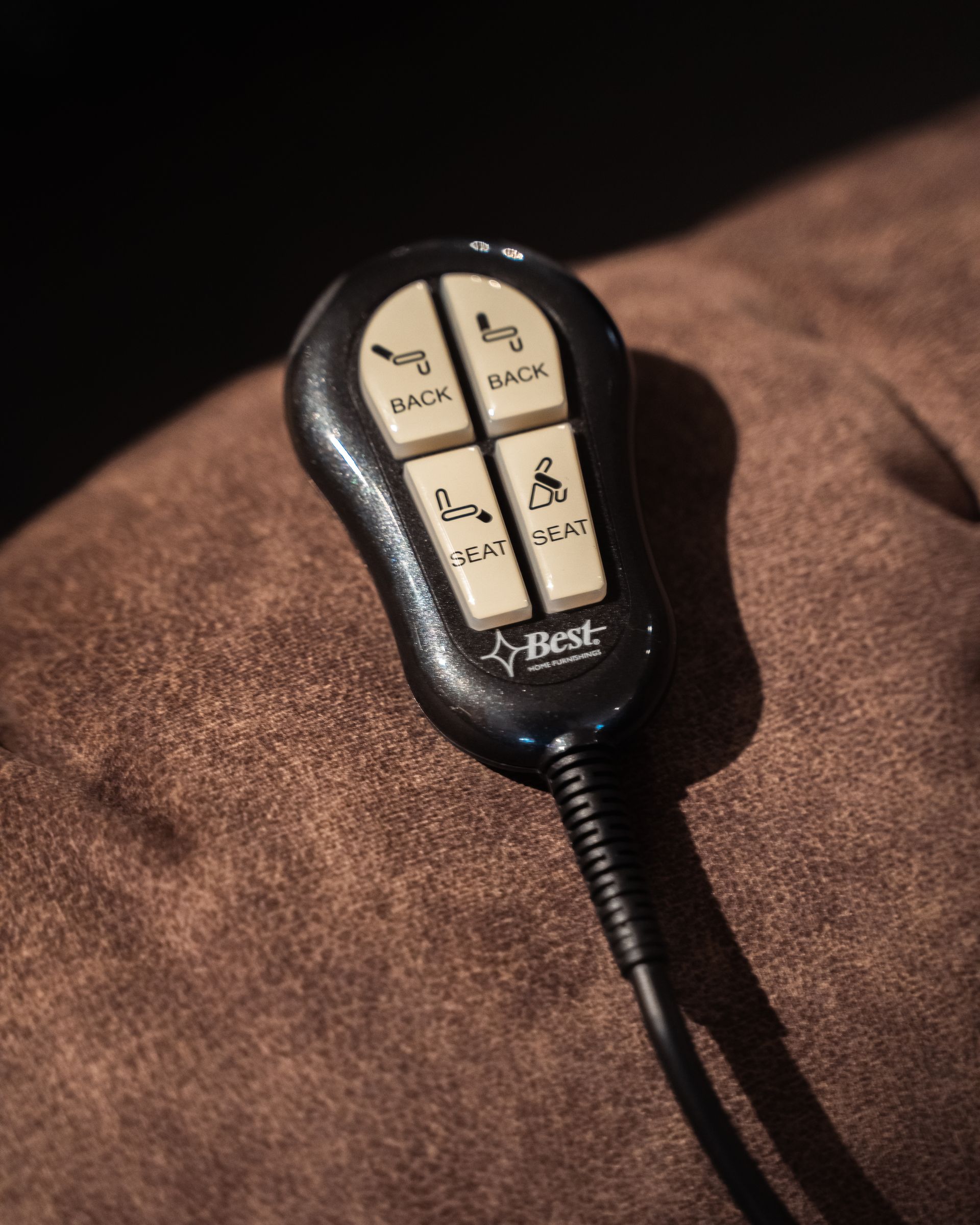 A best remote control is sitting on a brown couch