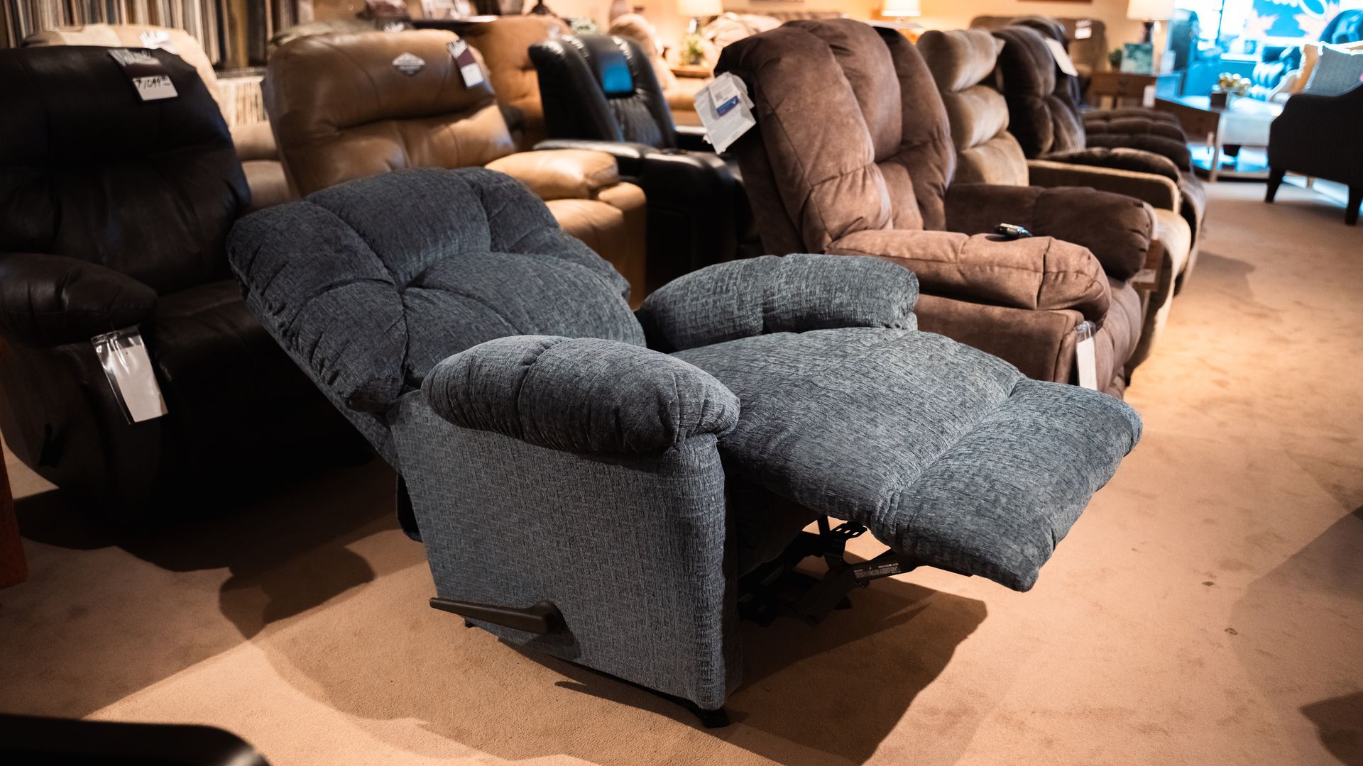 A row of recliner chairs are lined up in a store.