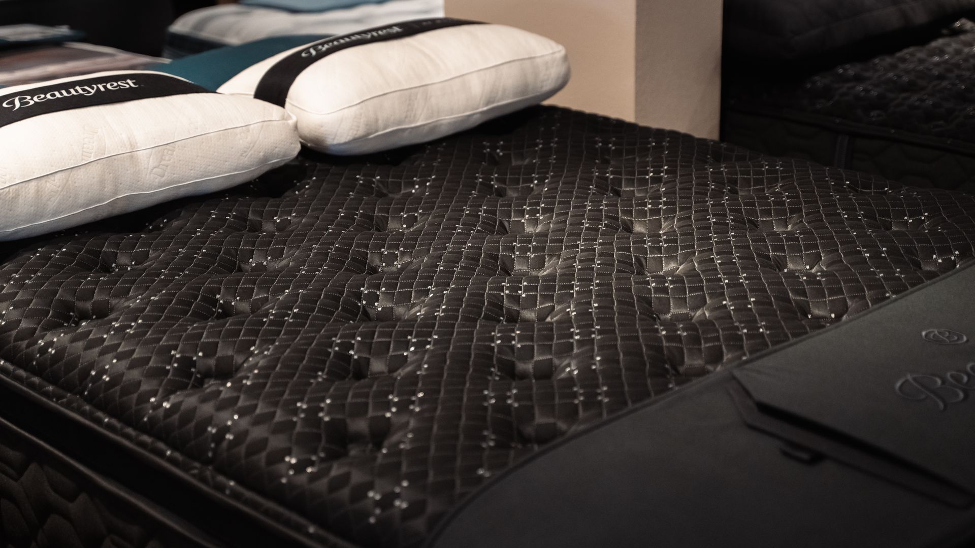 A black mattress with white pillows on top of it.