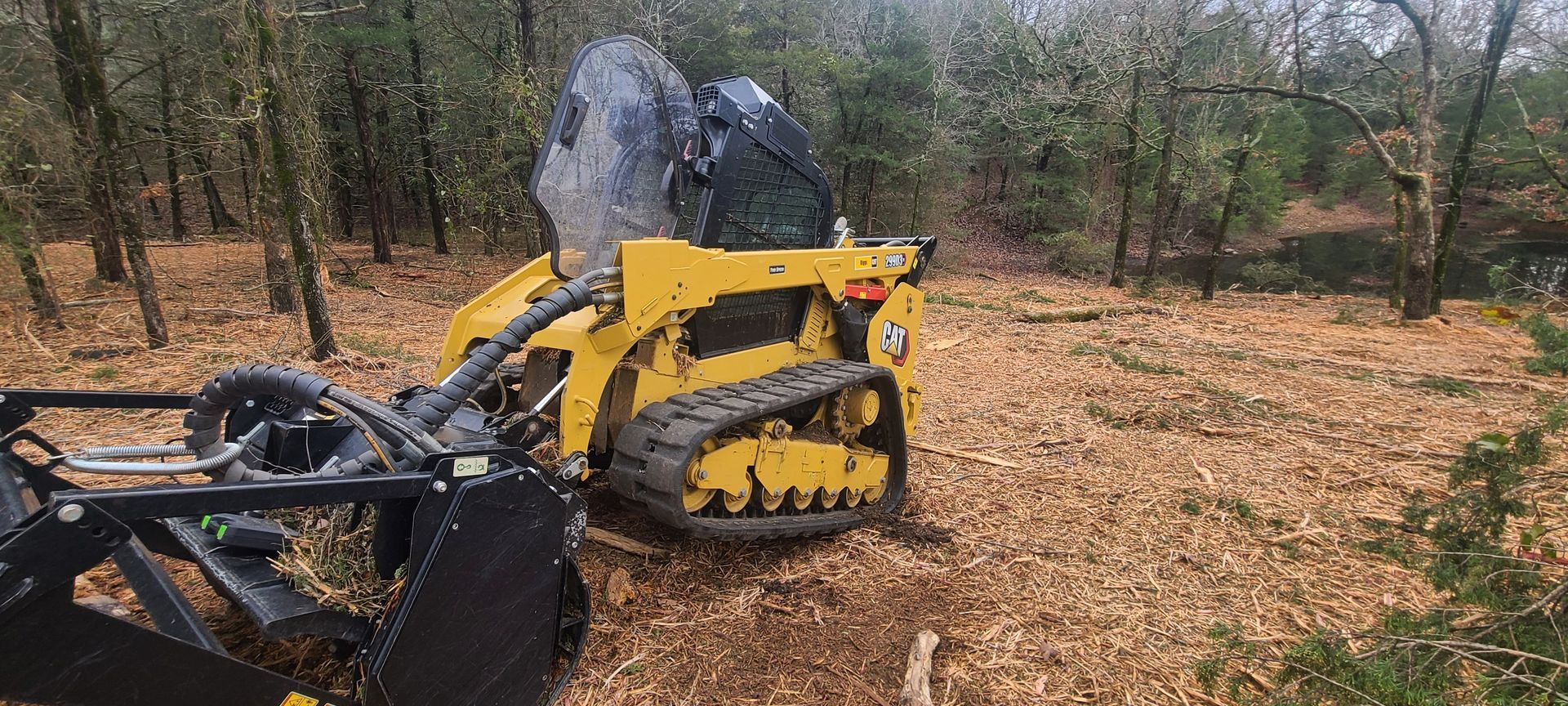 A yellow tractor is sitting in the middle of a forest.