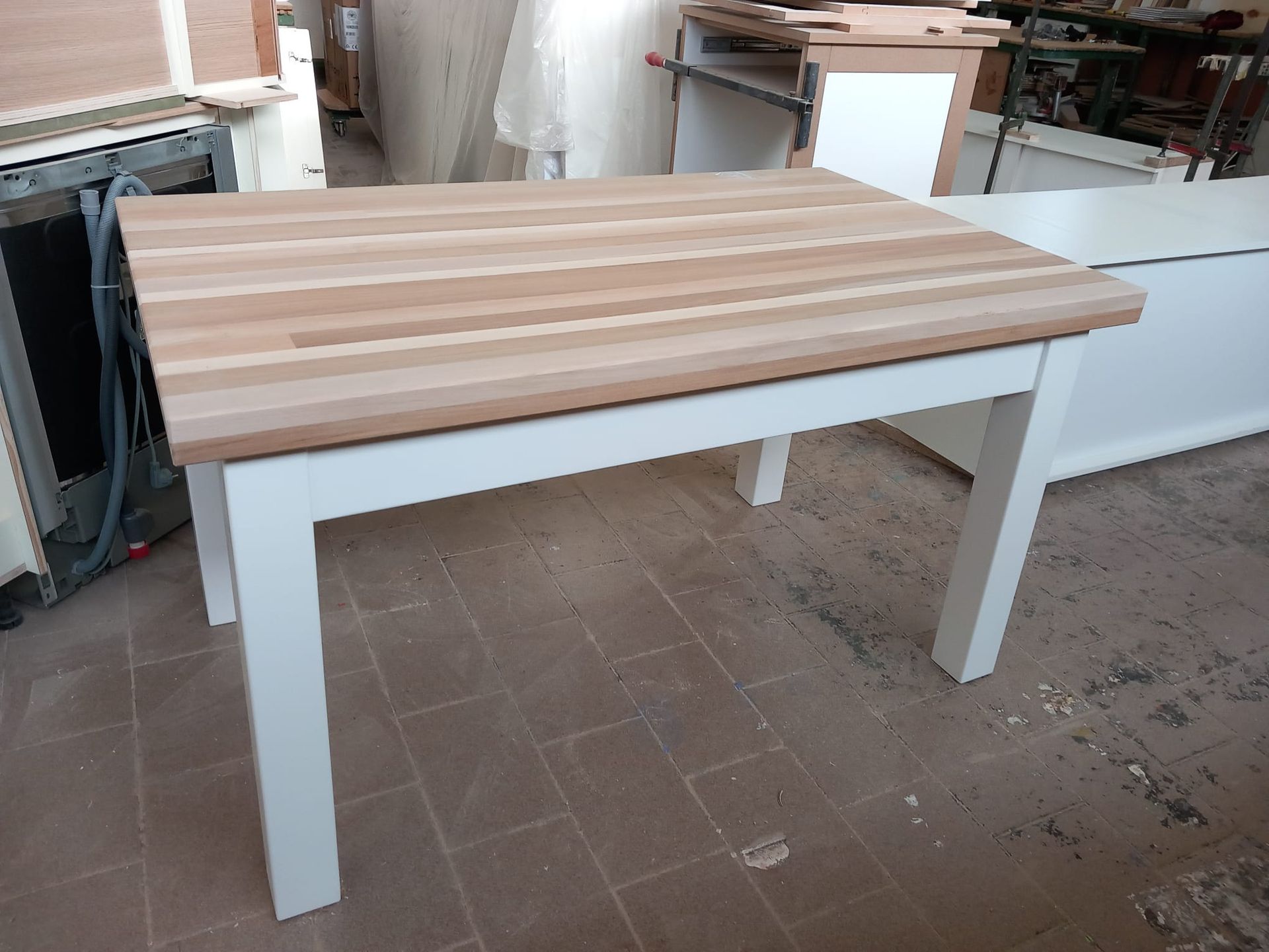 Tavolo con gambe bianche e piano in legno chiaro in un ambiente da laboratorio.