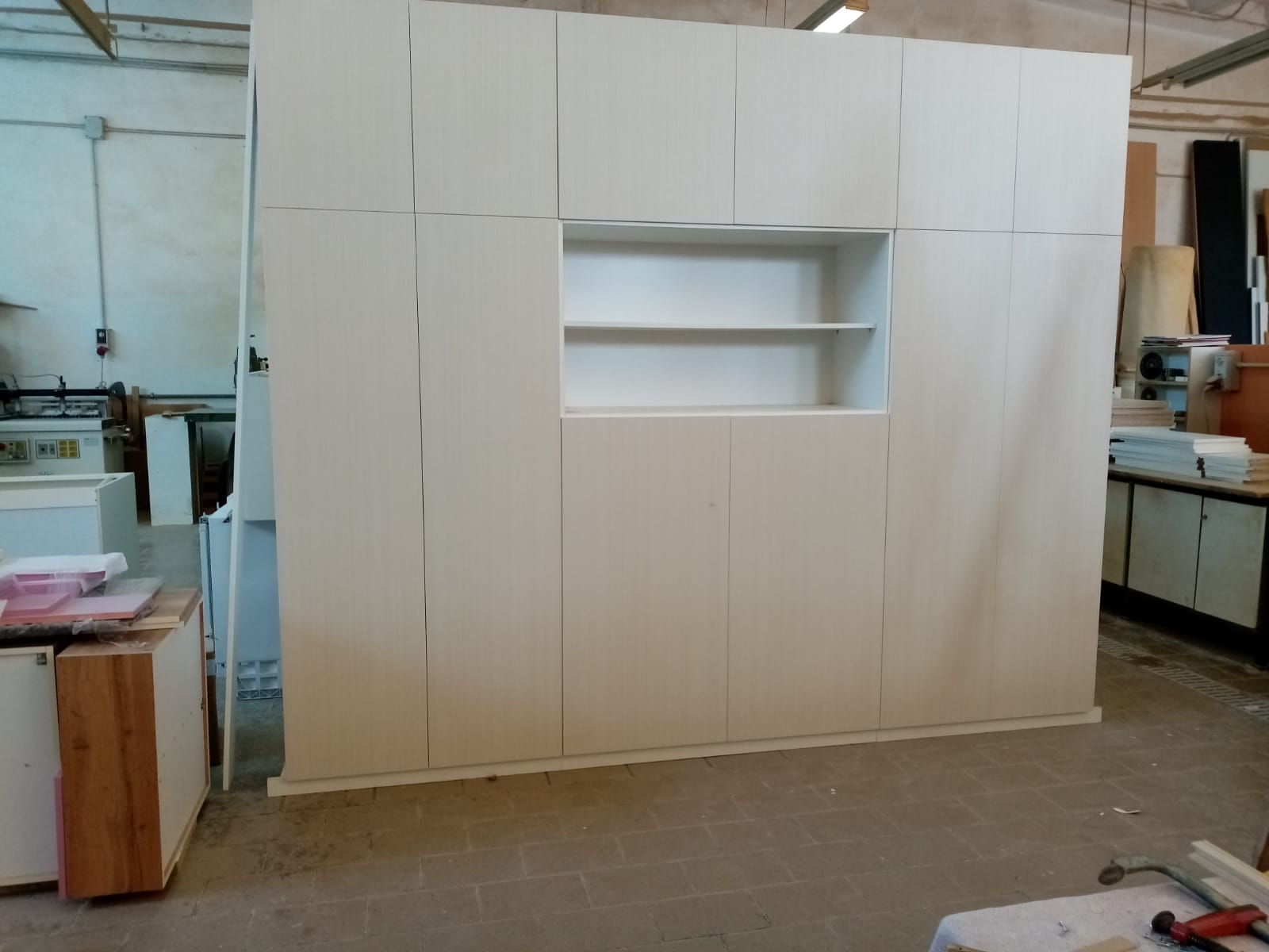 Grande armadio a muro bianco con scaffalature in un ambiente industriale.