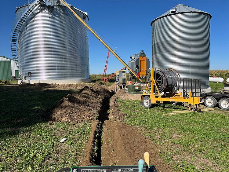 A trench is being dug in a field next to a building.
