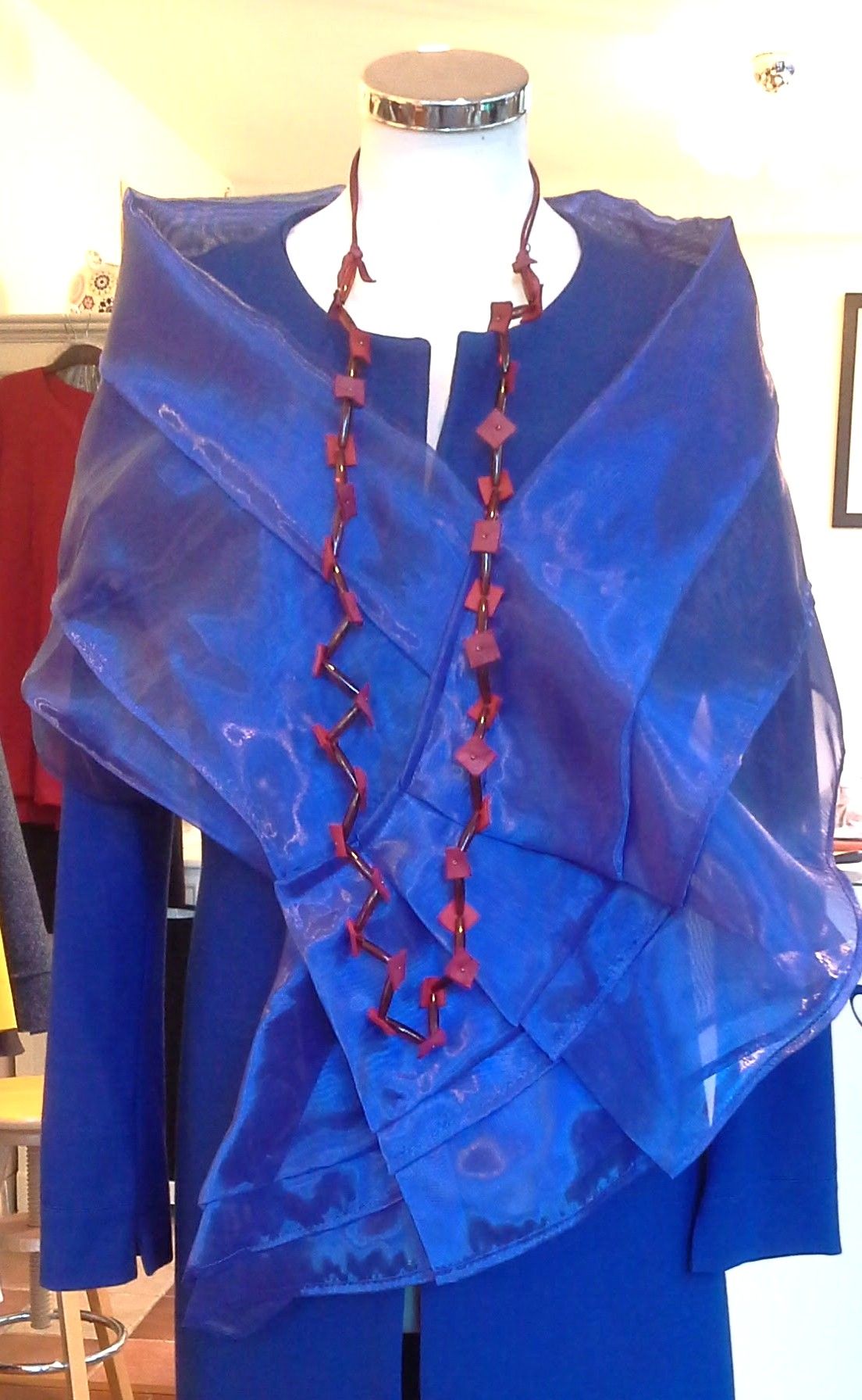 Een mannequin met een blauw jasje en een rode ketting