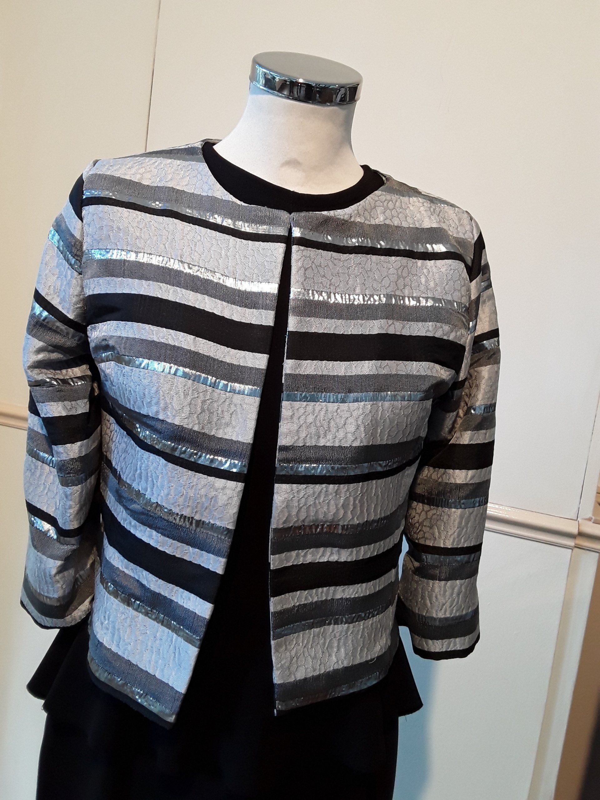 Een zwart en zilver gestreept jasje staat op een paspop