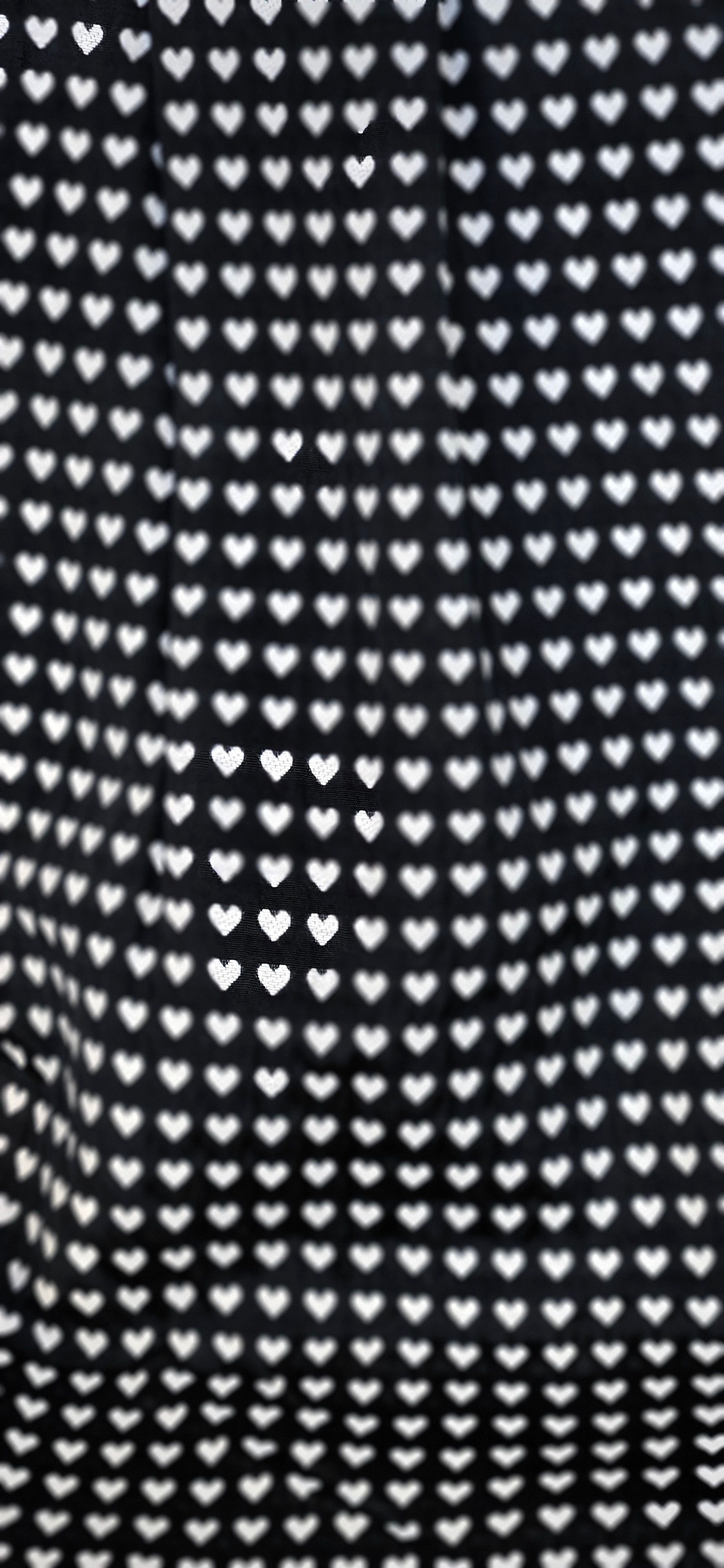 Een zwart-wit patroon van harten op een zwarte achtergrond.