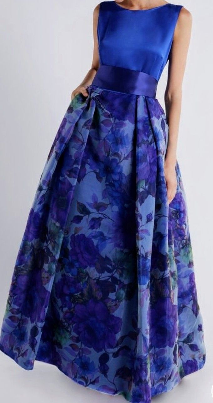 Een vrouw draagt ​​een feestelijke blauwe jurk met paarse bloemen erop