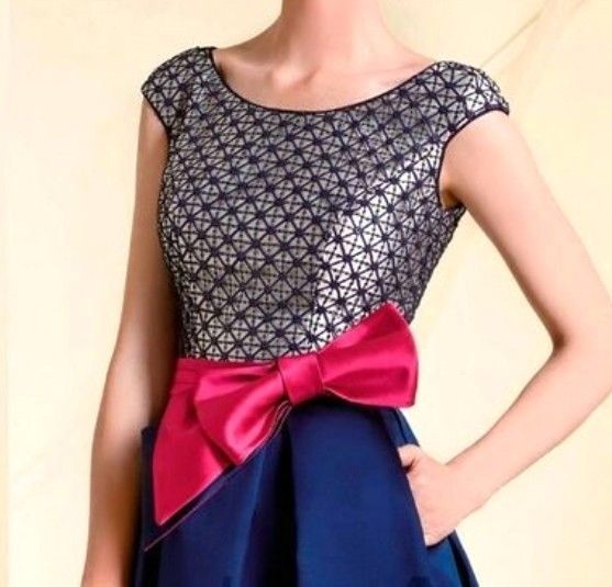 Een vrouw in een blauwe jurk + geruit topje, gescheiden door een roze heupstrik