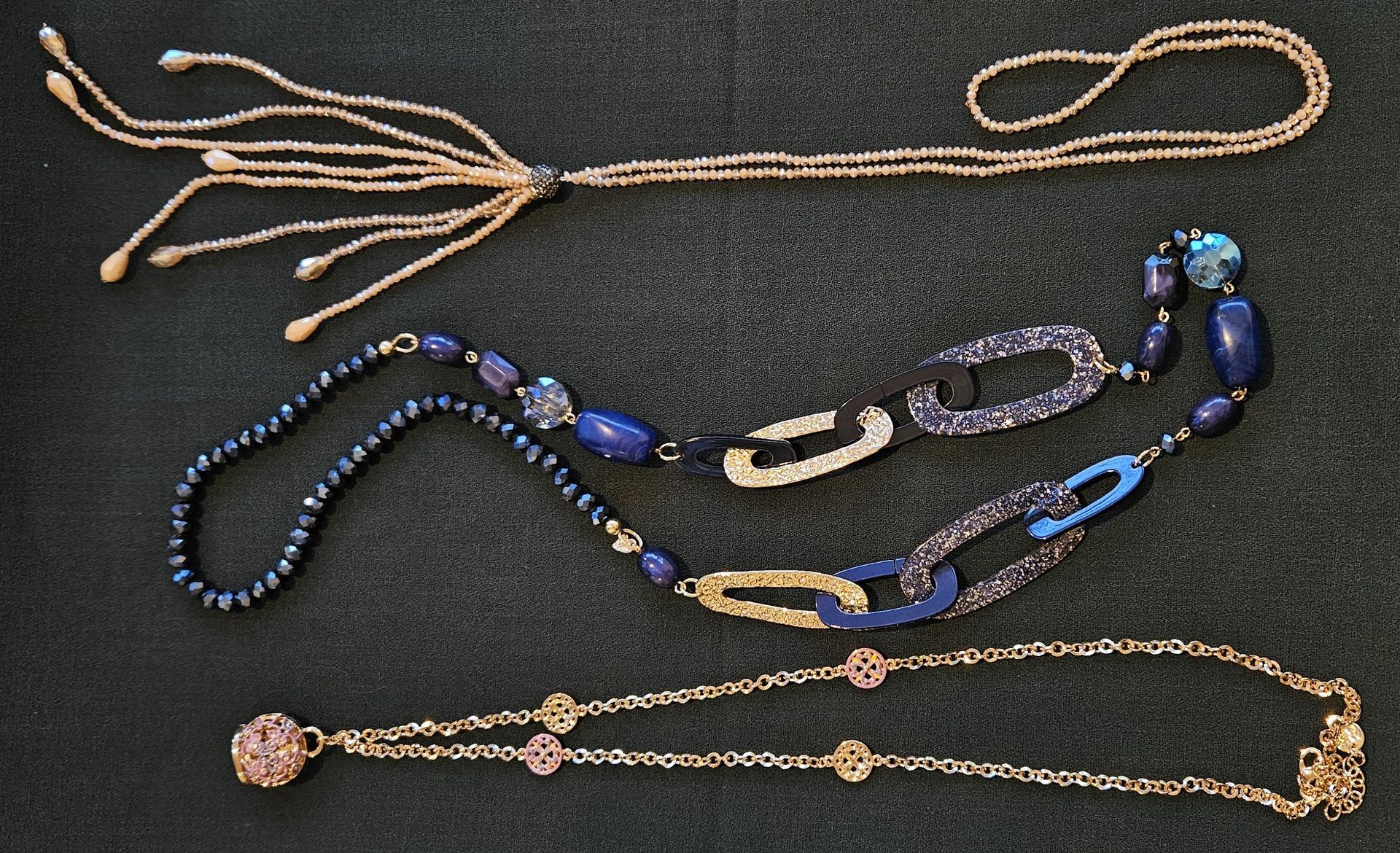 Drie kettingen liggen op een zwarte achtergrond