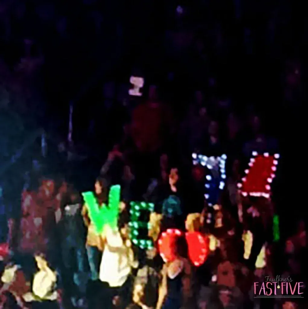 A crowd of people in a dark room with a sign that says fashion