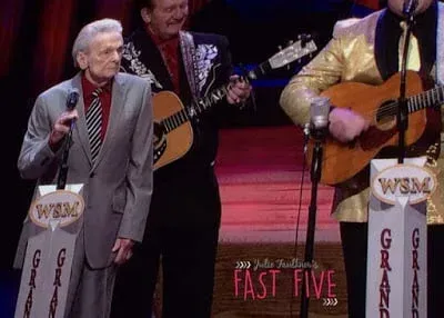 A group of men are standing on a stage playing guitars and singing into microphones.