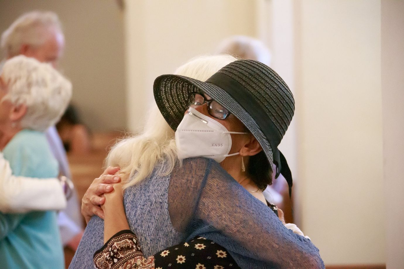 Two Parishioners hugging during the Peace of the People | Congregantes abrazándose durante la paz