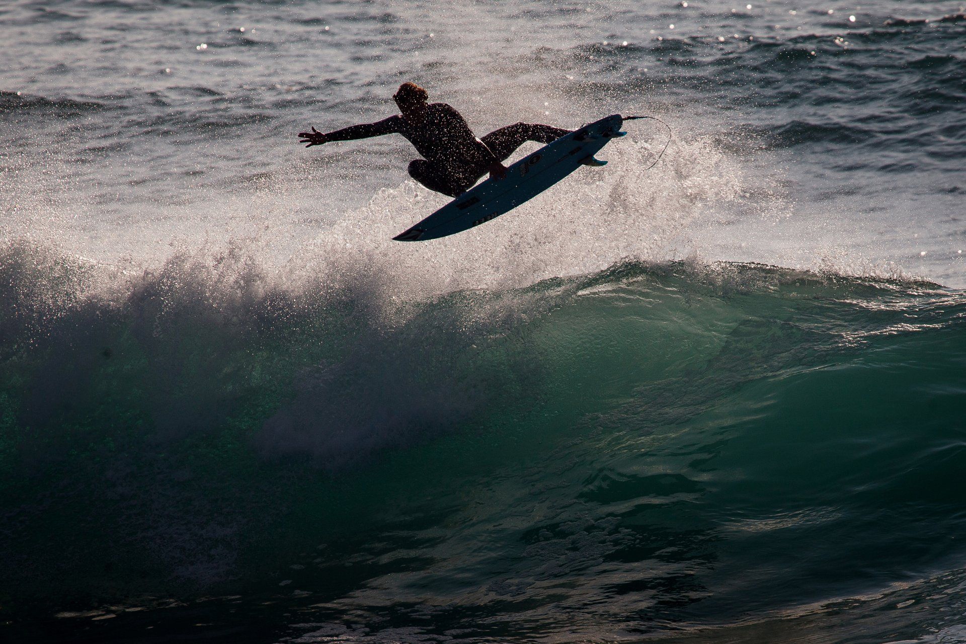 harry timson surfer gets air on firstral beach backlit wave