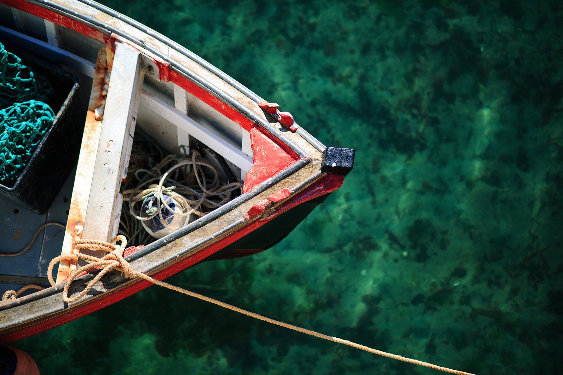 Fishing boat in Mousehole harbour floating on beautiful teal and green waters cornwall