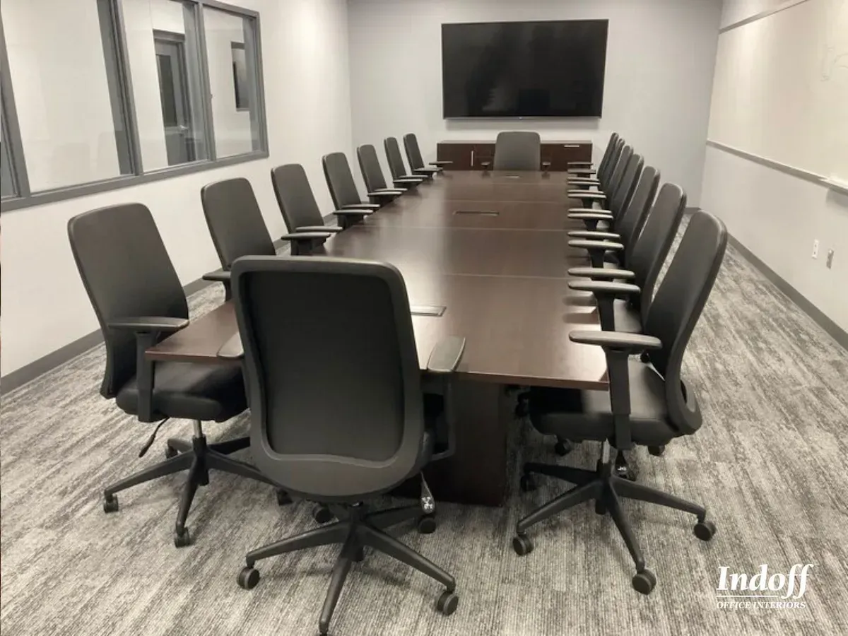A conference room with a long table and chairs and a flat screen tv.