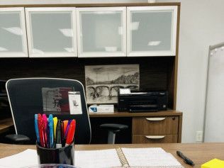 A desk with a chair and a cup of pens on it.