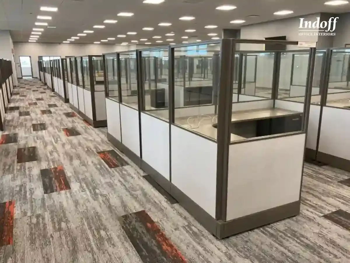 A row of cubicles in an office with a carpeted floor.