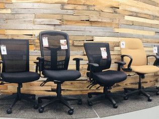 A row of office chairs sitting in front of a wooden wall.