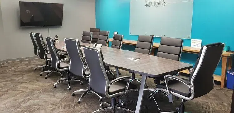 A conference room with a long table and chairs.