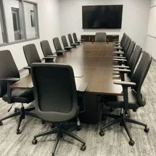 A conference room with a long table and chairs and a flat screen tv.