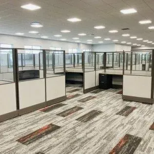 A large office with cubicles and a carpeted floor.