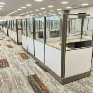 A row of cubicles in an office with a carpeted floor.