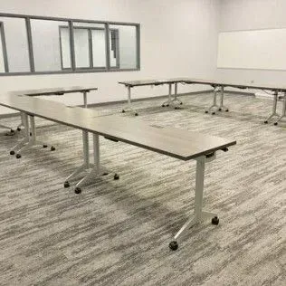 A classroom with a lot of tables and a whiteboard.