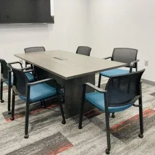 A conference room with a table and chairs and a flat screen tv.
