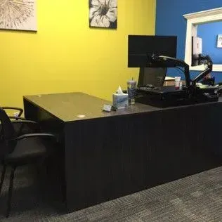 A desk with a computer on top of it in a room with yellow walls.