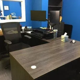 There is a desk with a chair and a computer on it.