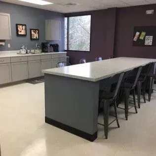 A kitchen with a long table and chairs in it.