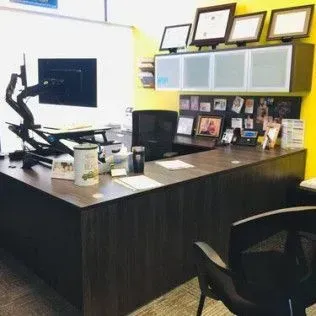There is a desk with a computer on it and a chair in the office.