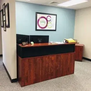 A reception desk in an office with a picture on the wall above it.