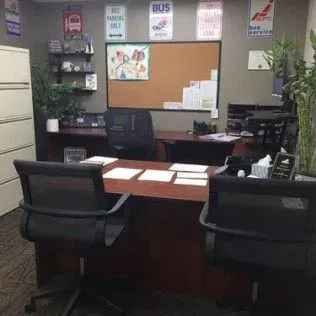 A office with a desk , chairs , and a cork board.