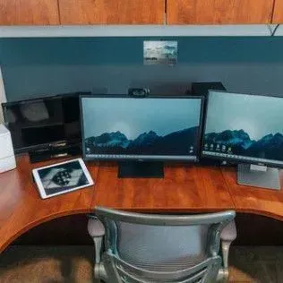 A desk with two monitors and a tablet on it
