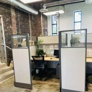 A room with cubicles and a desk with a computer on it.