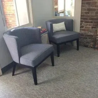 Two chairs are sitting next to each other in a room with a brick wall.